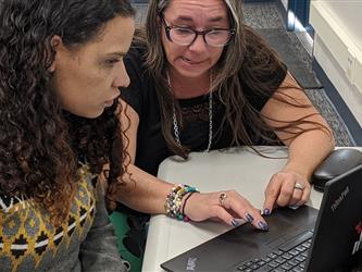 teachers working together in front of a laptop