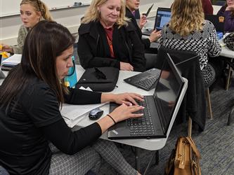 teachers working together in front of a laptop