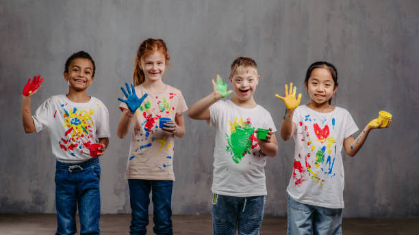 Four happy children with paint on their hands.