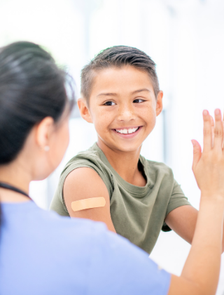 boy slapping hands with medical personnel and bandaid on arm 